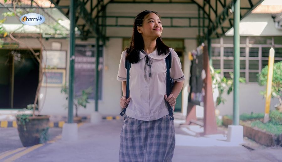A Filipina student in her puberty wearing a school uniform and a backpack walking through a school hallway